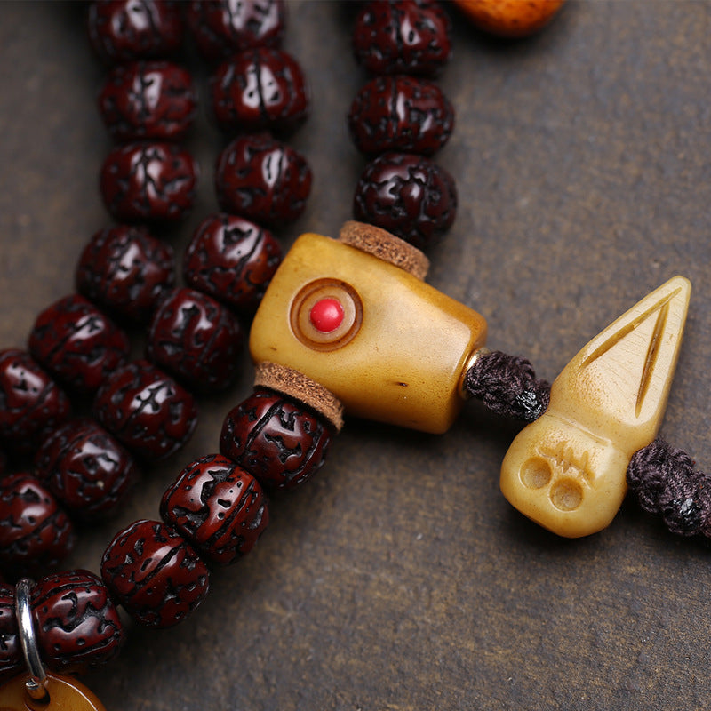 Detail of carved bone A-Dai guru bead and bone arrow pendant with red agate accent