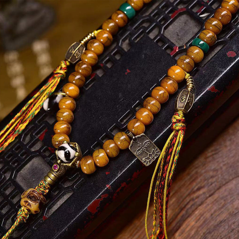 Full yak bone 108 mala laid flat on dark lacquer box showing bone guru bead, dzi bead and lotus tag pendant