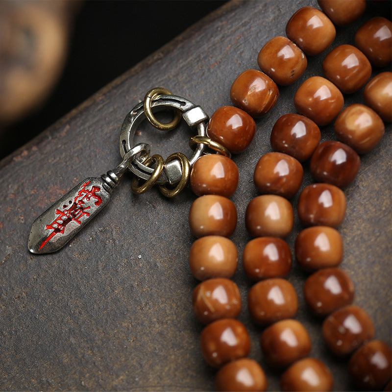 Detail of vintage brass charm and swastika spacer bead on cocos barrel bead mala