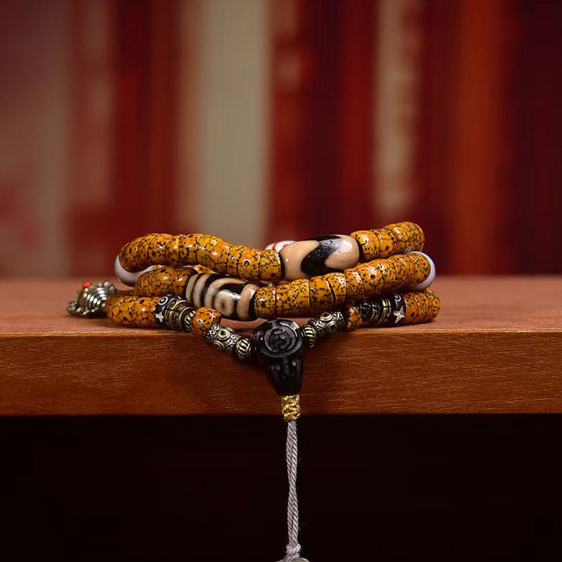 Crescent star bodhi mala wrapped as multi-loop bracelet on wooden surface showing dorje and metal charms