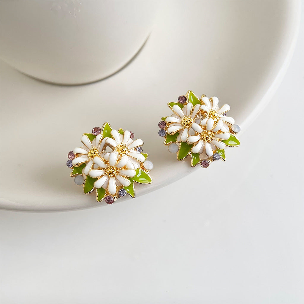 Pair of white daisy enamel stud earrings on white plate