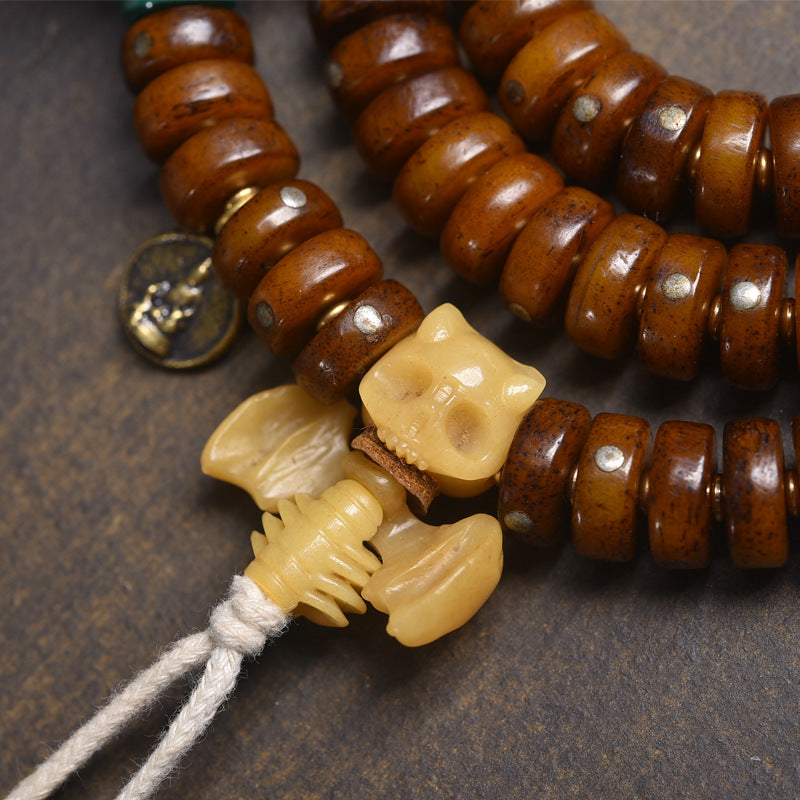 Close-up of hand-carved bone Pixiu charm and silver medallion pendant on recycled bone disc mala