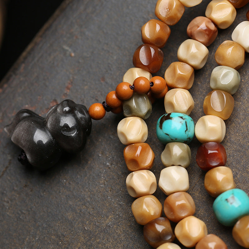 Detail of carved obsidian skull pendant and turquoise spacer beads on dragon spine bodhi mala