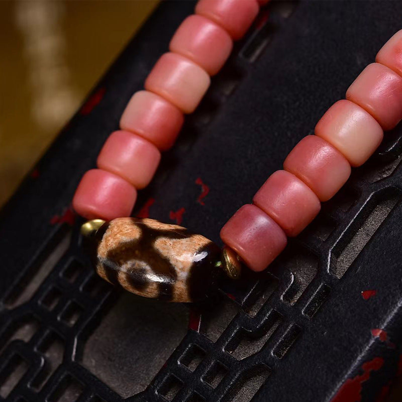 Close-up of vintage dzi stone accent bead with gold cap on half-red yak bone mala