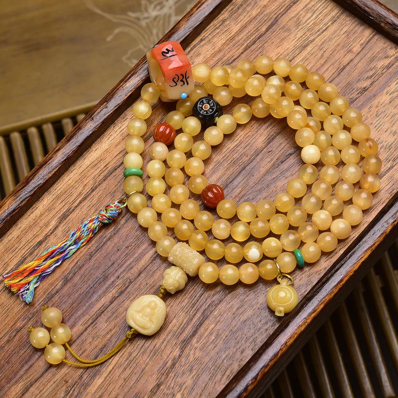 Antler mala on wooden tray with red dzi bead, black eye bead, bone Buddha pendant and colorful tassel