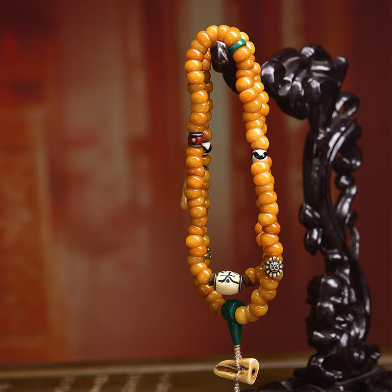 Yak bone disc mala hanging on carved wooden stand showing drape
