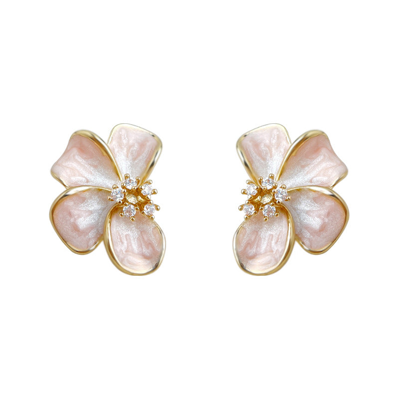 Pair of pink enamel floral stud earrings displayed on white ceramic