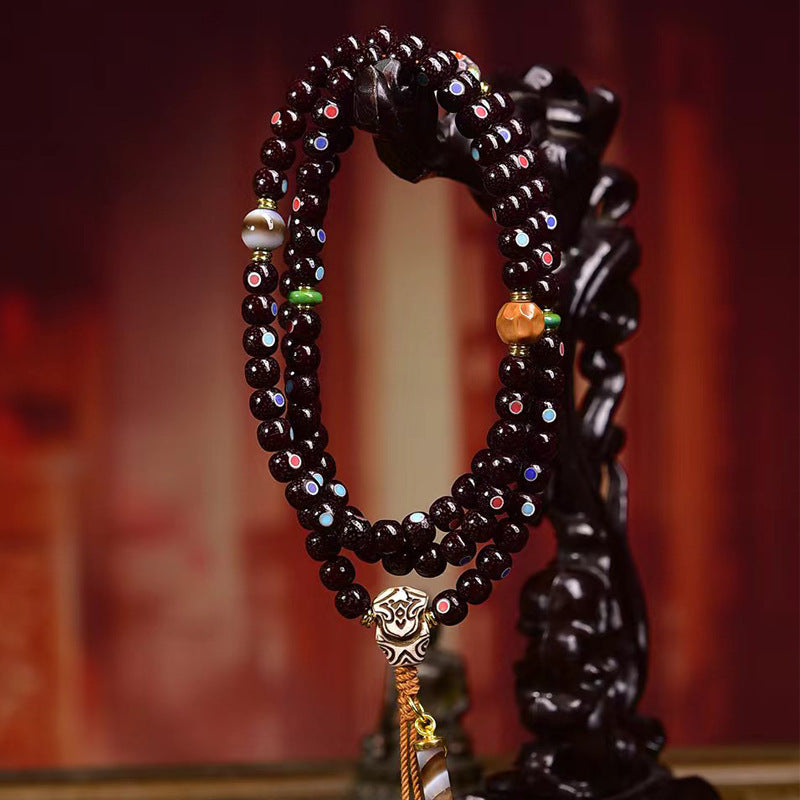 Cinnabar bodhi mala hanging on carved wooden Pixiu stand showing double-wrap drape and charms