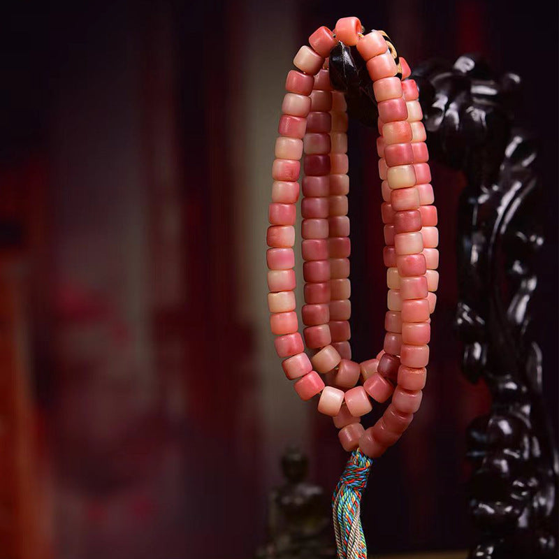 Half-red yak bone 108 mala hanging on black carved figurine stand showing full length and colorful tassel