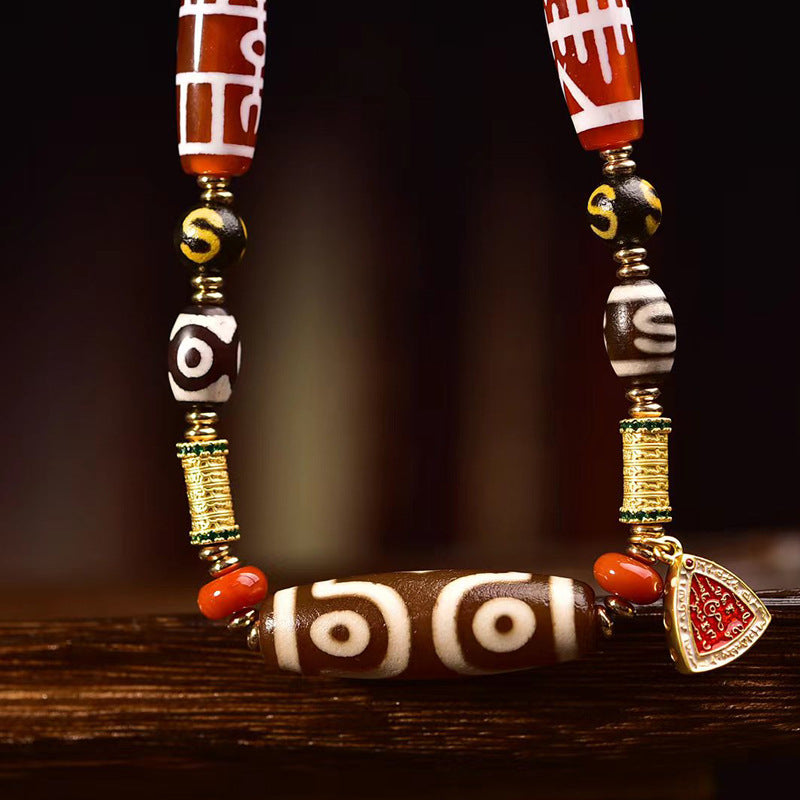 Close-up of dzi bead with brass spacers and triangular enamel charm