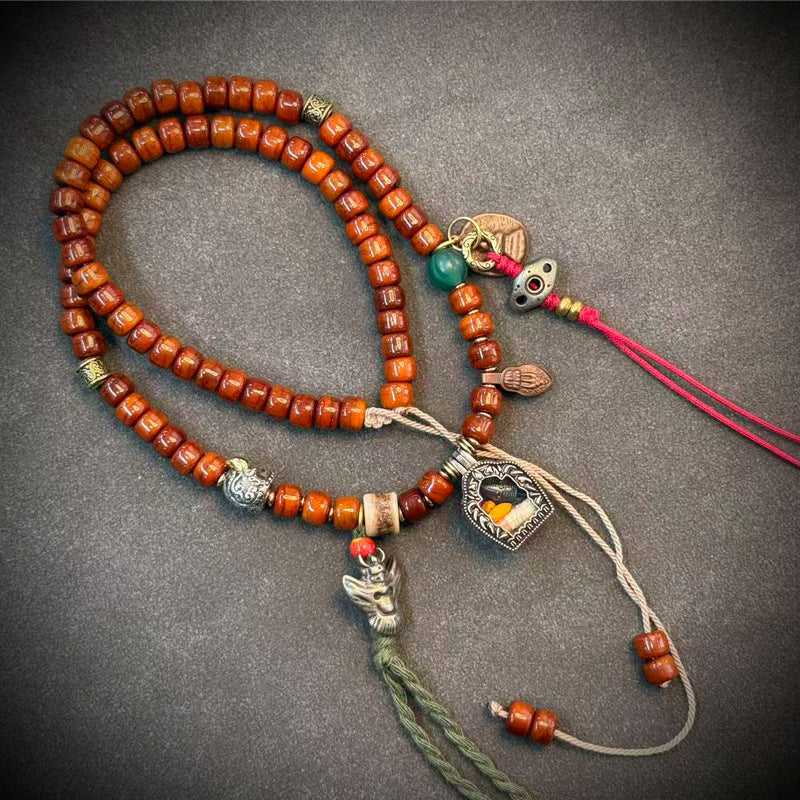 Yak bone mala on grey surface with silver heart locket pendant and turquoise bead
